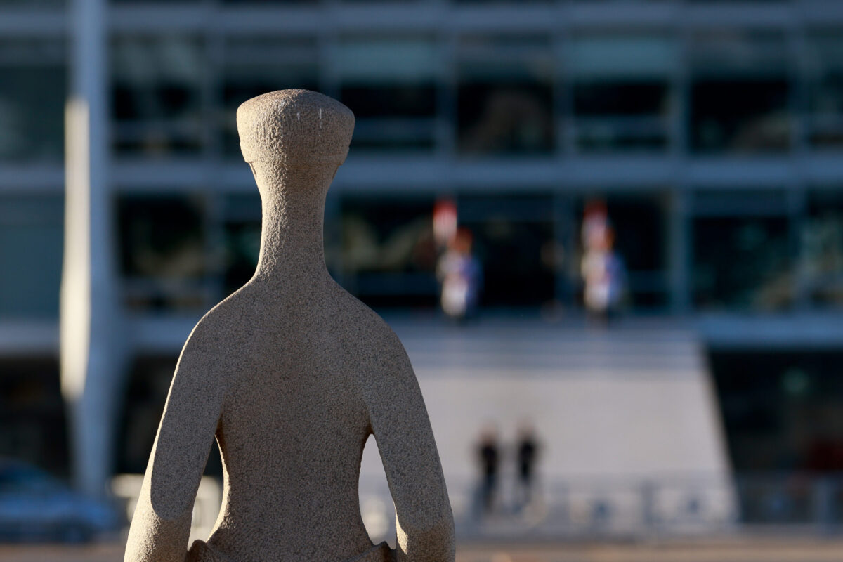 Estátua da Justiça, localizada na Praça dos Três Poderes, no primeiro plano, com o Palácio do Planalto à frente, no segundo plano.