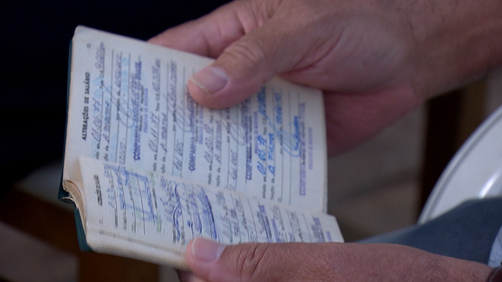 Detalhe de pessoa manuseando carteira de trabalho bastante usada