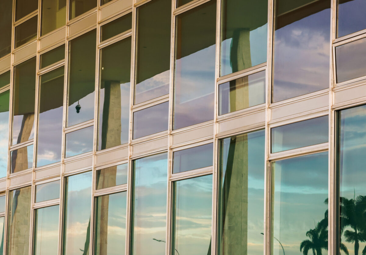 Foto colorida na horizontal da vidraça do prédio do STF, com reflexo dos arcos do prédio sede