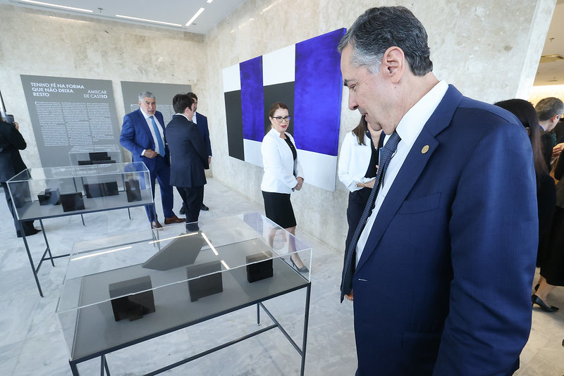 Ministro Luís Roberto Barroso olhando peças da exposição dispostas em uma mesa