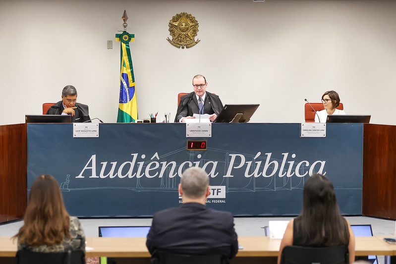 Ministro Cristiano Zanin presidindo a audiência pública sentado na bancada da sala de sessões da Primeira Turma e demais pessoas