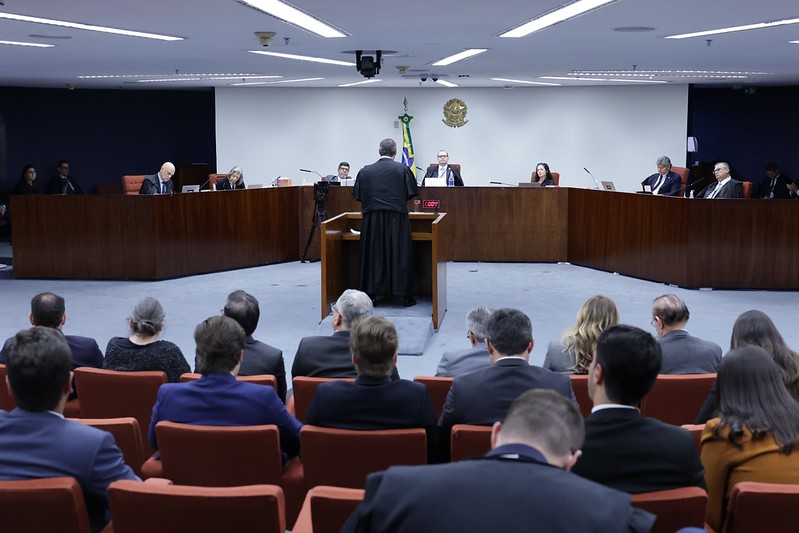 Advogado de costas sustentando no púlpito de frente para a bancada com os ministros durante o julgamento