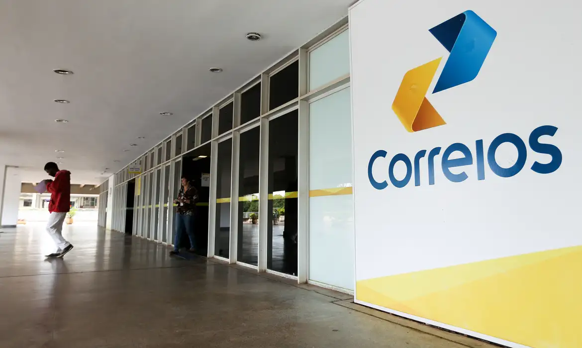 Foto de um homem negro saindo de uma agência dos Correios