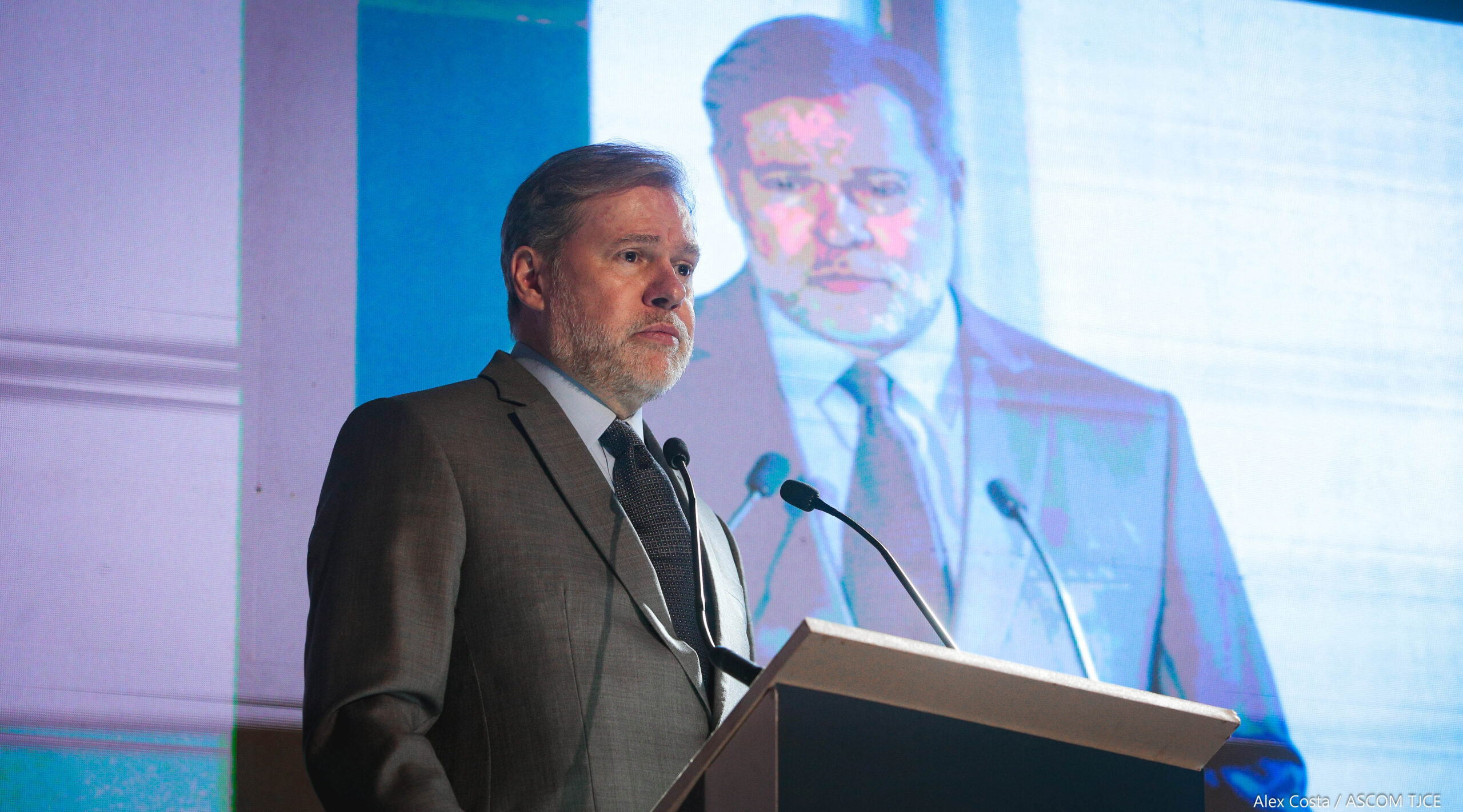 Ministro Dias Toffoli faleceu em púlpito no evento. Atrás dele aparece um telão com sua imagem.