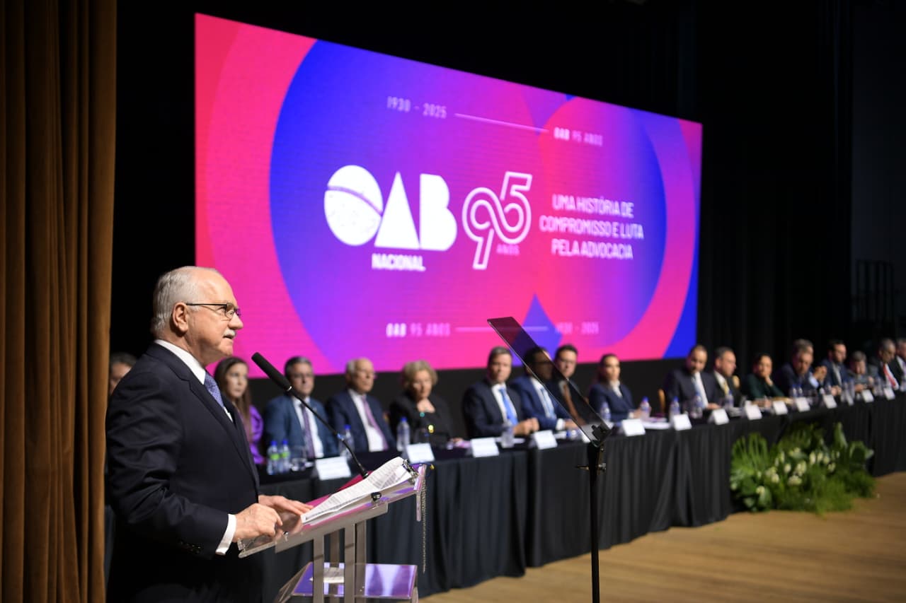 Fotografia do ministro Edson Fachin à esquerda, falando em um púlpito. Do lado direito, os demais integrantes da mesa do evento.