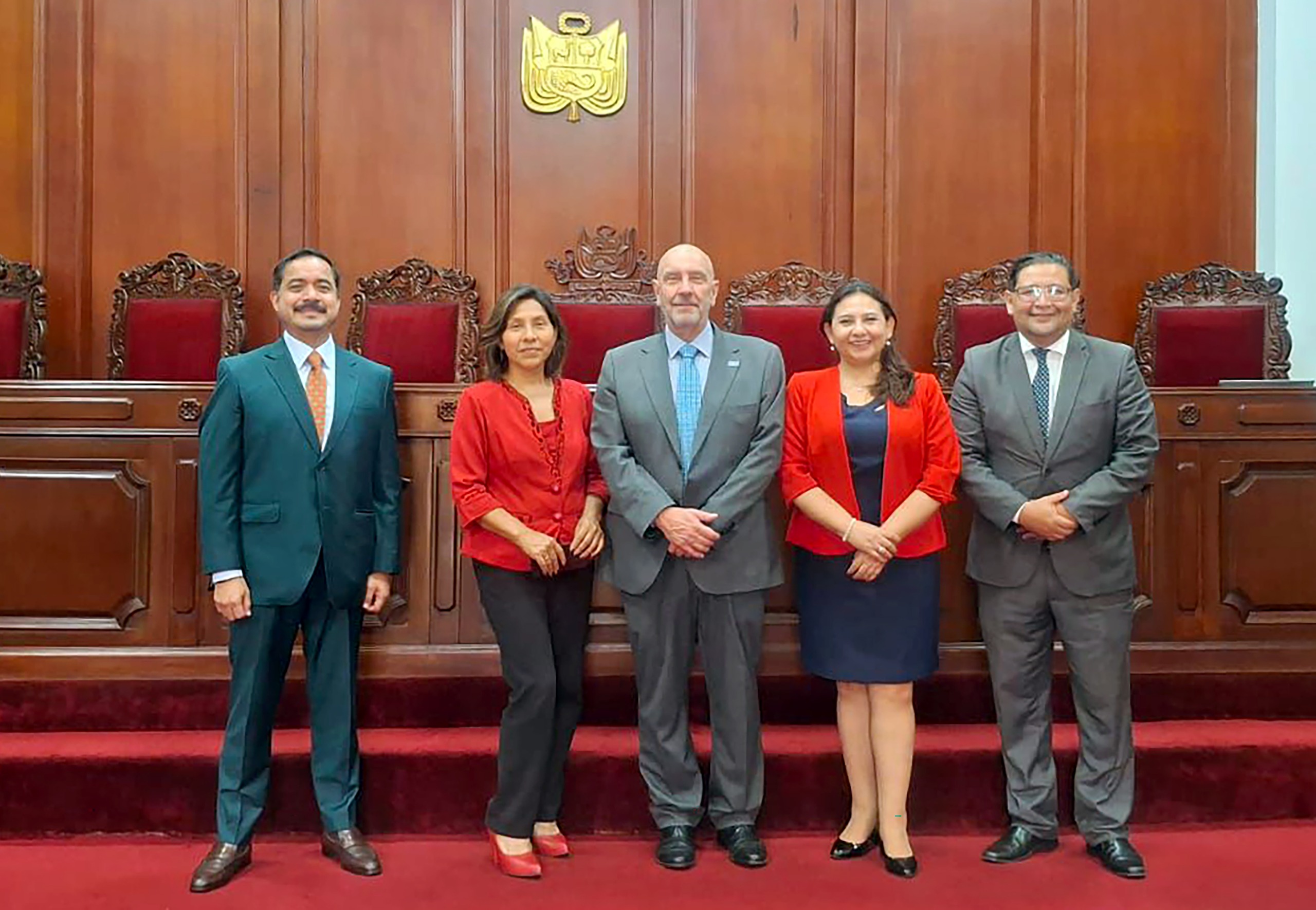 Fotografia de cinco pessoas perfiladas, três homens e duas mulheres, na sala do Tribunal Constitucional do Peru