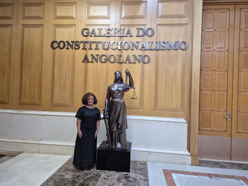 Juíza Franciele Nascimento ao lado de uma estatua representando a Justiça, diante da Galeria do Constitucionalismo Angolano