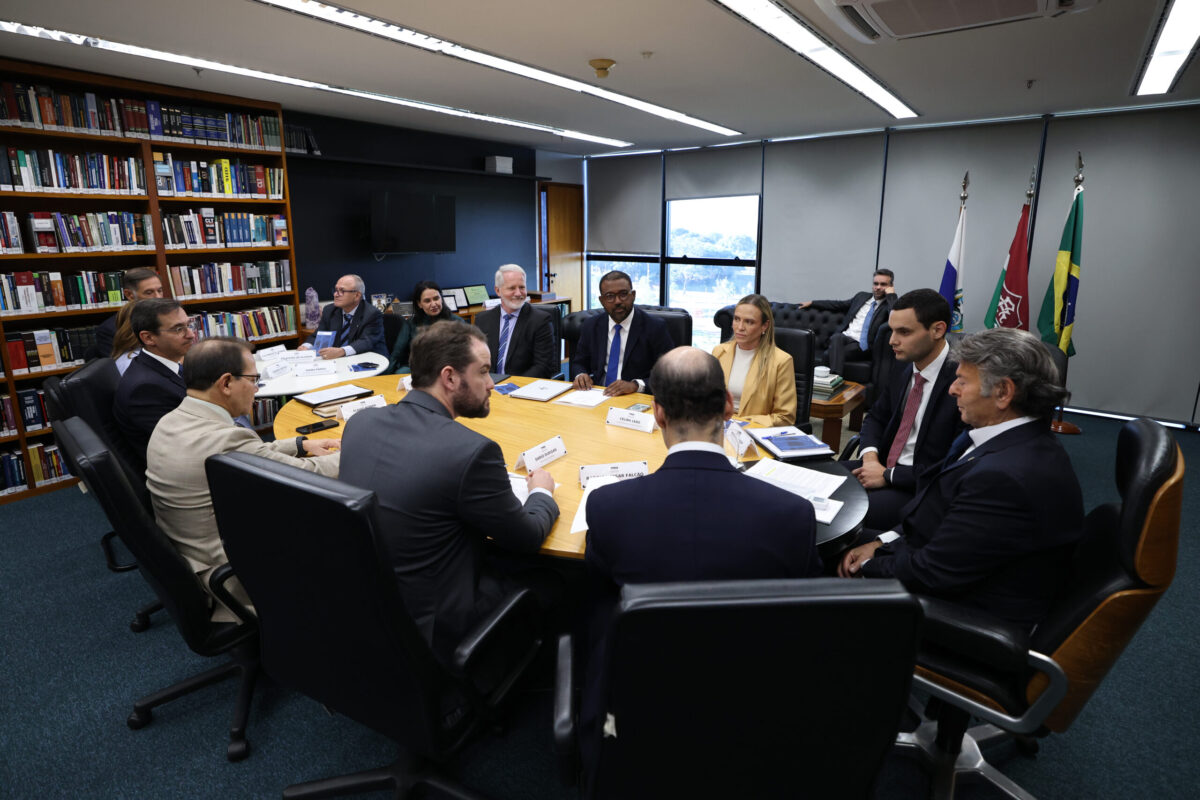 Fotografia colorida dos participantes da audiência sentados em volta de uma mesa.