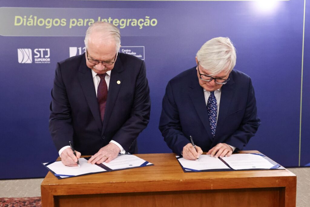 Fotografia dos ministros Edson Fachin e Herman Benjamin assinam acordo.