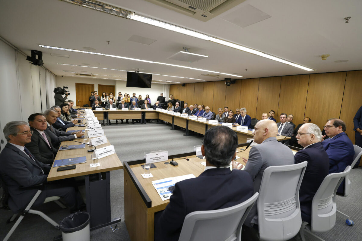 Fotografia da mesa com todos os participantes da reunião.